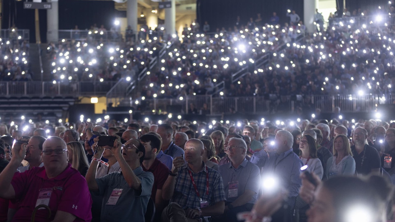 A gathered audience holding up hundreds of bright phone lights.
